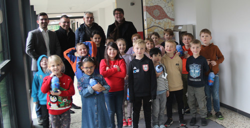 Einer Gruppe von Grundschüler:innen posierten anlässlich der Trinkbrunnenspende mit Dr. Ralf Levacher, OB Marc Speicher, Bürgermeister Carsten Quirin, Beigeordneter Gerald Purucker.