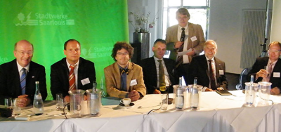 Zeigt die  Podiumsdiskussion mit Professor Wahlster, Holger Kirchner, Prof. Müller-Quade, Dr. Levacher, Peter Zayer (Voltaris) und Prof. Mühlhäuser (v.l.n.r. – stehend Ludwig Karg) an einem Tisch sitzen.